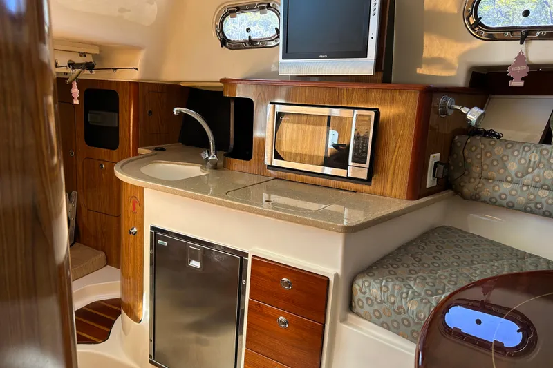 Slide: The Image of 2008 Pursuit OS 315 Offshore boat interior with kitchenette, microwave, and seating area. - 18