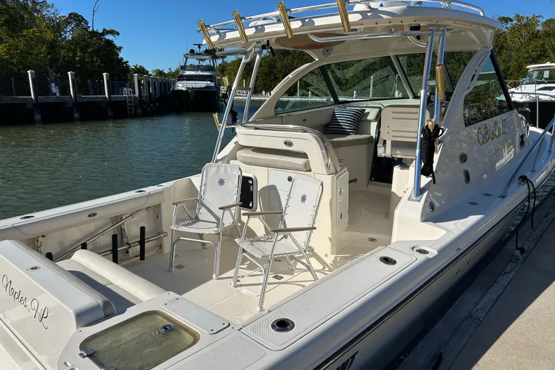 Slide: The Image of 2008 Pursuit OS 315 Offshore boat docked, featuring spacious seating and fishing rod holders. - 3