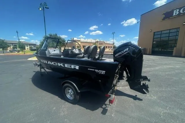 Slide: The Image of 2026 Tracker Pro Guide V-16 WT boat with Mercury engine in a parking lot. - 2