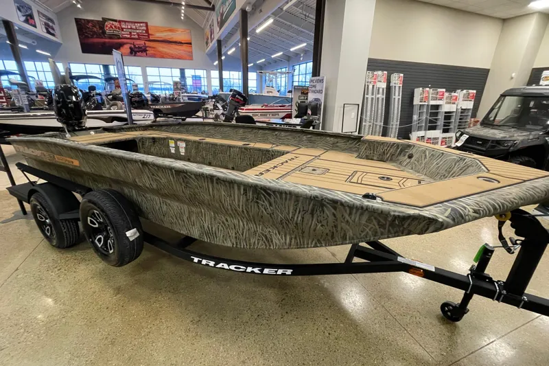 The Image of 2026 Tracker Grizzly 1756 T Marsh boat displayed in showroom, featuring camouflage design. - 0