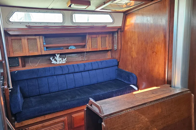 Slide: The Image of Interior of 1989 ENDEAVOR 42 sailboat with blue cushioned seating and wooden cabinetry. - 34