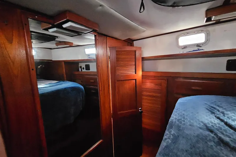 Slide: The Image of Cozy cabin interior of 1989 ENDEAVOR 42 sailboat with wooden furnishings and blue bedding. - 44