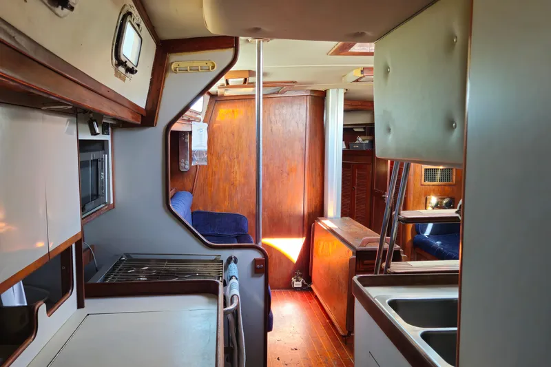 Slide: The Image of Interior of 1989 ENDEAVOR 42 sailboat, featuring kitchen and seating area with wood accents. - 51