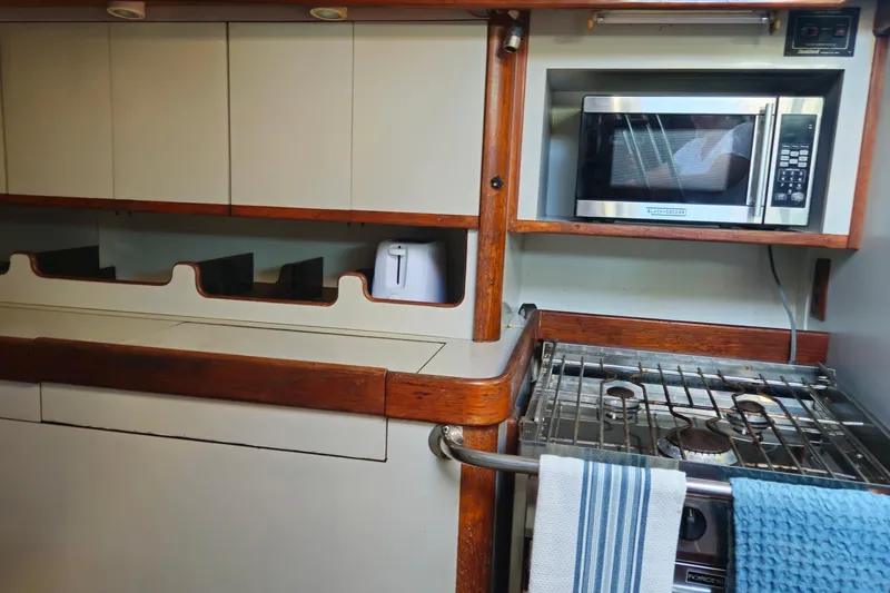 Slide: The Image of 1989 ENDEAVOR 42 yacht kitchen with microwave, stove, and wooden cabinetry. - 54