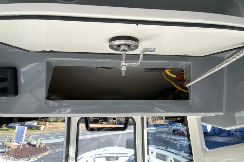 Slide: The Image of 2026 Cobia 245 Center Console boat interior storage compartment with wiring and latch mechanism. - 36