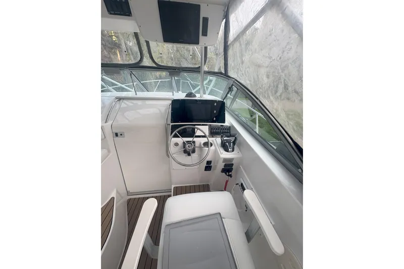 Slide: The Image of 2001 Boston Whaler 285 Conquest cabin interior with seating, table, and compact kitchen area. - 11