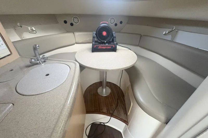 Slide: The Image of 2001 Boston Whaler 285 Conquest cabin interior with seating, table, and compact kitchen area. - 6