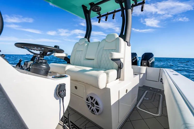 Slide: The Image of 2026 Reef Runner 340 boat interior with white seating, steering wheel, and ocean backdrop. - 19