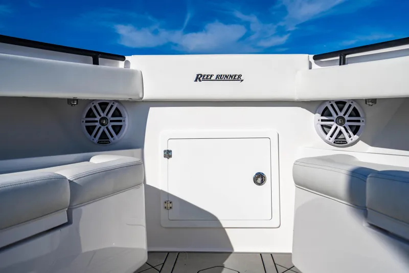 Slide: The Image of 2026 Reef Runner 340 boat interior with speakers and storage, under a clear blue sky. - 25