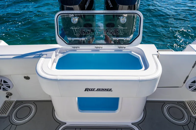 Slide: The Image of 2026 Reef Runner 340 boat with open livewell, featuring sleek design and ocean backdrop. - 6