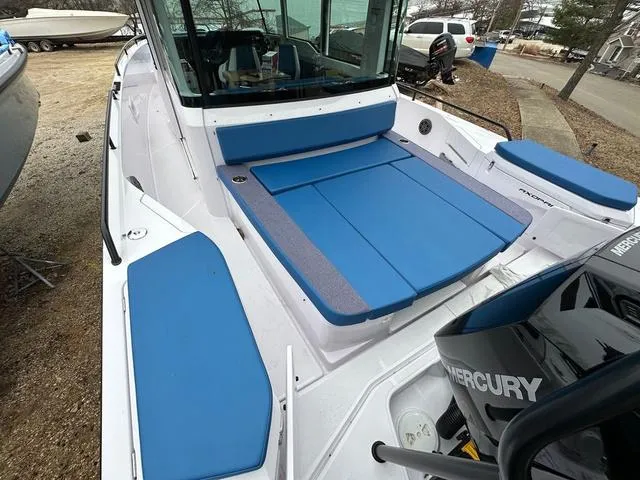 Slide: The Image of 2025 Axopar 37 XC Cross Cabin interior with blue seating and wooden table, overlooking water. - 4