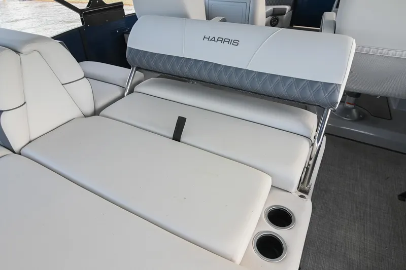 Slide: The Image of 2021 Harris Sunliner 230 boat interior with white cushioned seating and cup holders. - 18