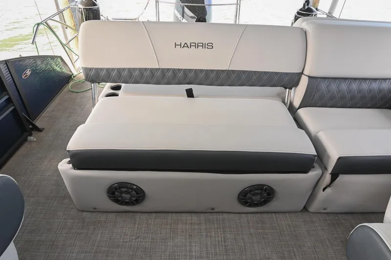Slide: The Image of 2021 Harris Sunliner 230 boat interior with cushioned seating and built-in speakers. - 20