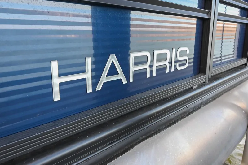 Slide: The Image of 2021 Harris Sunliner 230 pontoon boat with sleek blue exterior and bold logo. - 4