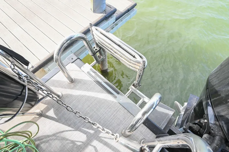 Slide: The Image of 2021 Harris Sunliner 230 boat ladder and dock, with green water below. - 5