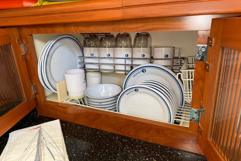 Slide: The Image of Cabinet with Hunter-branded dishes and glasses, neatly organized in a wooden kitchen setting. - 25