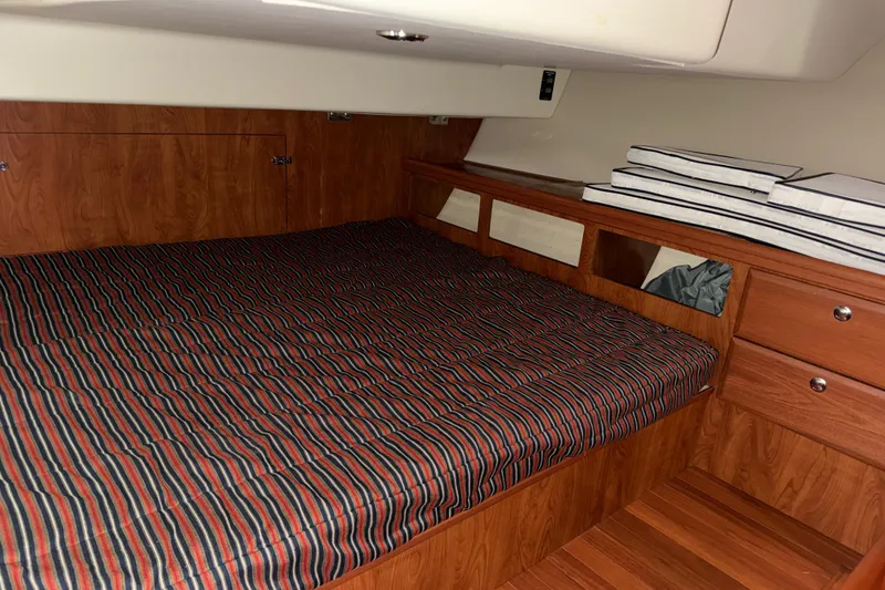 Slide: The Image of Cozy cabin interior of 2011 Hunter 39 sailboat with striped bedding and wooden finish. - 26