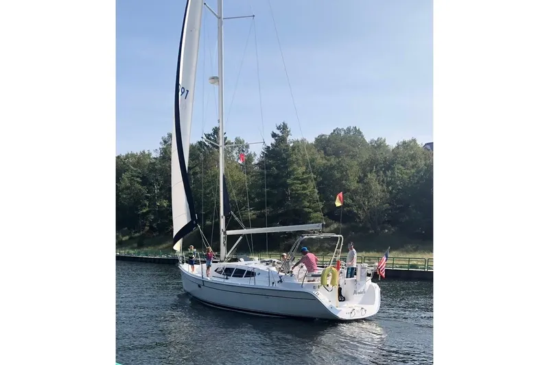 Slide: The Image of 2011 Hunter 39 sailboat cruising on a calm waterway with lush greenery in the background. - 7