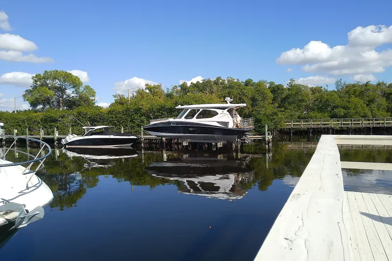 Slide: The Image of 2019 Floe Craft 3950C Aquafina boat docked on a serene, sunny waterfront. - 3