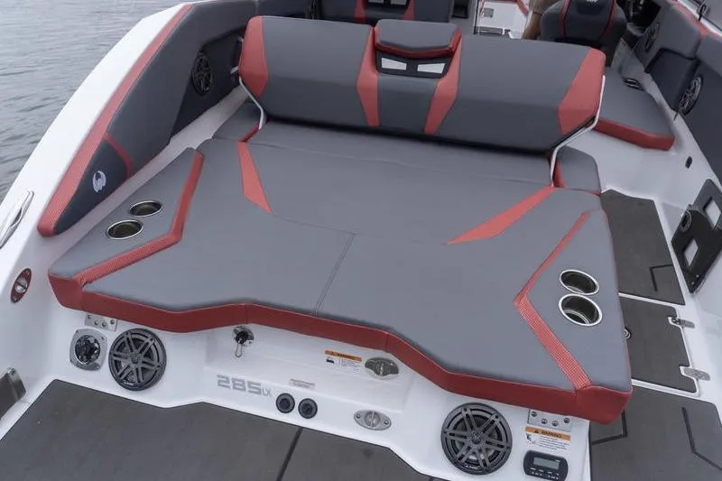 Slide: The Image of 2026 Scarab 285 LX Wake boat interior with gray and red seating, cup holders, and speakers. - 25