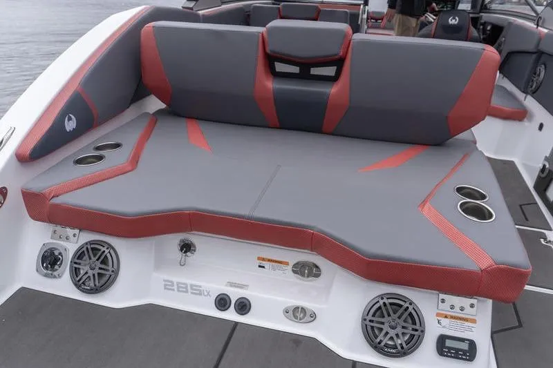 Slide: The Image of 2026 Scarab 285 LX Wake boat interior with gray and red seating, cup holders, and speakers. - 26