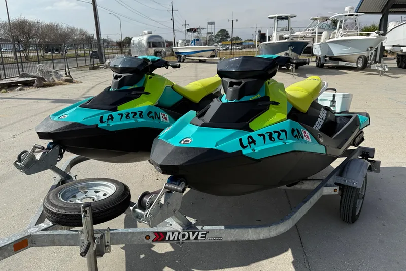 Slide: The Image of 2022 Sea-Doo Spark 3up jet skis on trailer, vibrant colors, parked outdoors. - 3