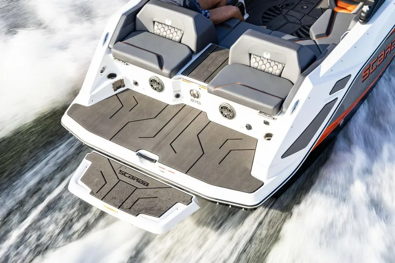 Slide: The Image of Manufacturer Provided Image: 2026 Scarab 210 LX Wake boat, rear view, on water, showcasing sleek design and seating. - 6
