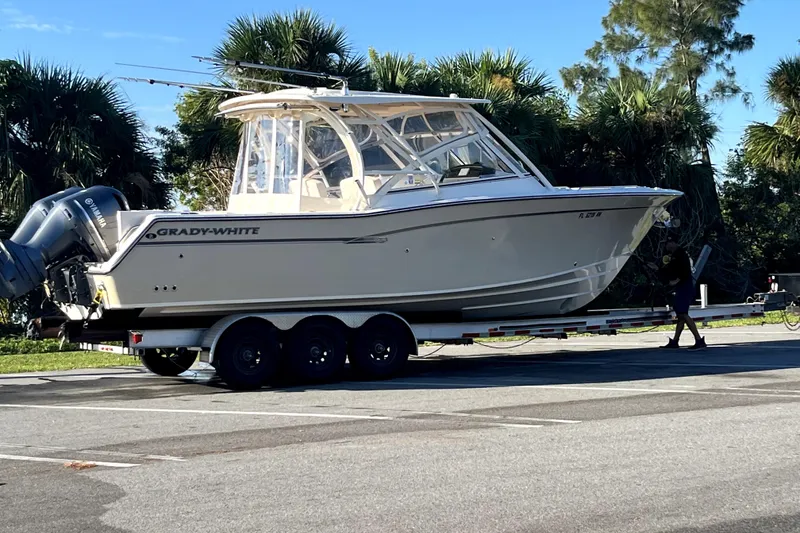 Slide: The Image of 2017 Grady-White Freedom 307 boat on trailer in parking lot, surrounded by trees. - 2