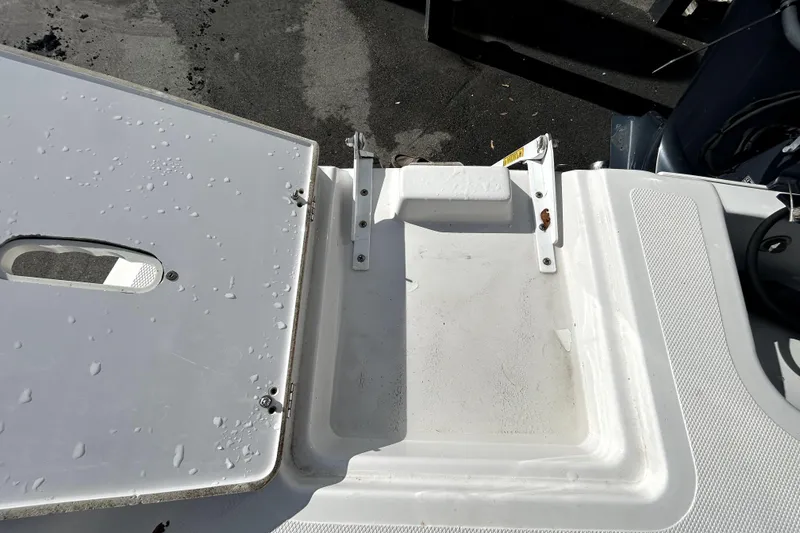 Slide: The Image of 2018 Four Winns HD240 boat deck with wet surface and open storage compartment. - 34