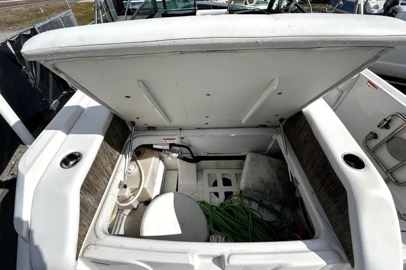 Slide: The Image of 2018 Four Winns HD240 boat storage compartment with open hatch, revealing interior equipment. - 36
