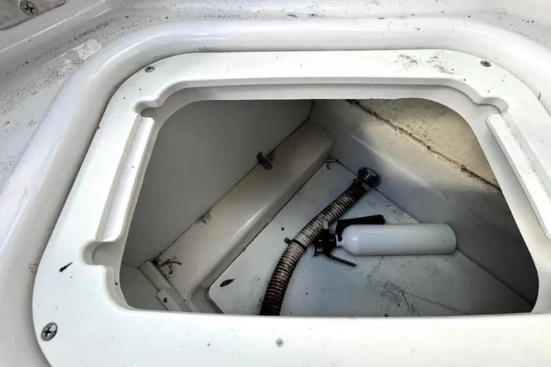 Slide: The Image of Storage compartment of 2018 Four Winns HD240 boat with hose and white canister. - 53