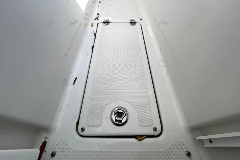 Slide: The Image of 2018 Four Winns HD240 boat storage compartment with latch, showing some debris. - 73