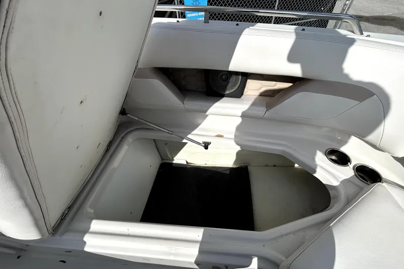 Slide: The Image of 2018 Four Winns HD240 boat storage compartment with open lid and cup holders. - 77