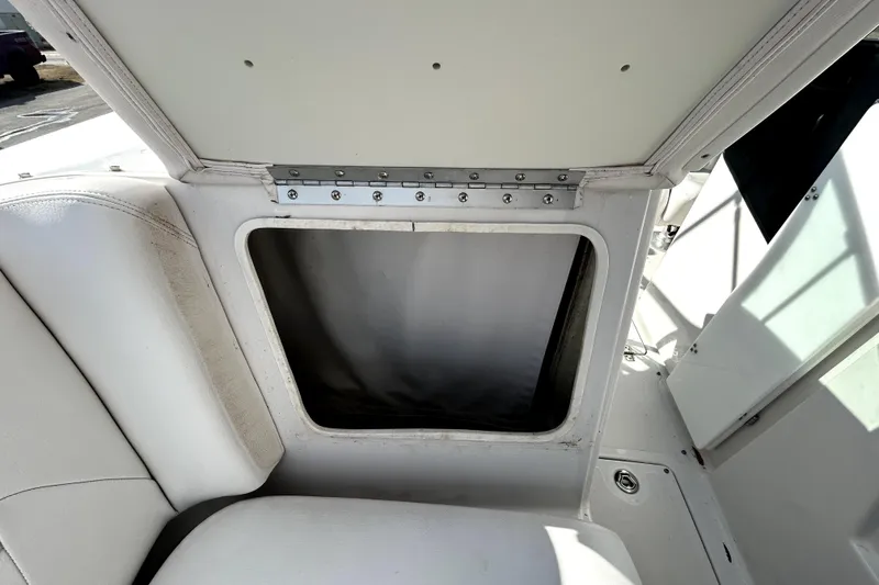 Slide: The Image of 2018 Four Winns HD240 boat storage compartment with white interior and open hatch. - 86
