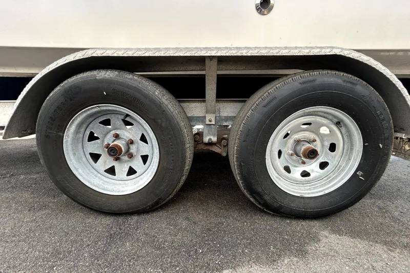 Slide: The Image of Trailer wheels of a 2018 Four Winns HD240 boat on asphalt surface. - 90