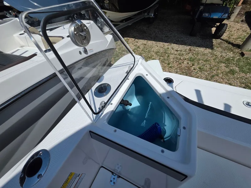 Slide: The Image of An open storage compartment on a Yamaha 222 FSH Sport E boat, with a blue hose inside. - 13
