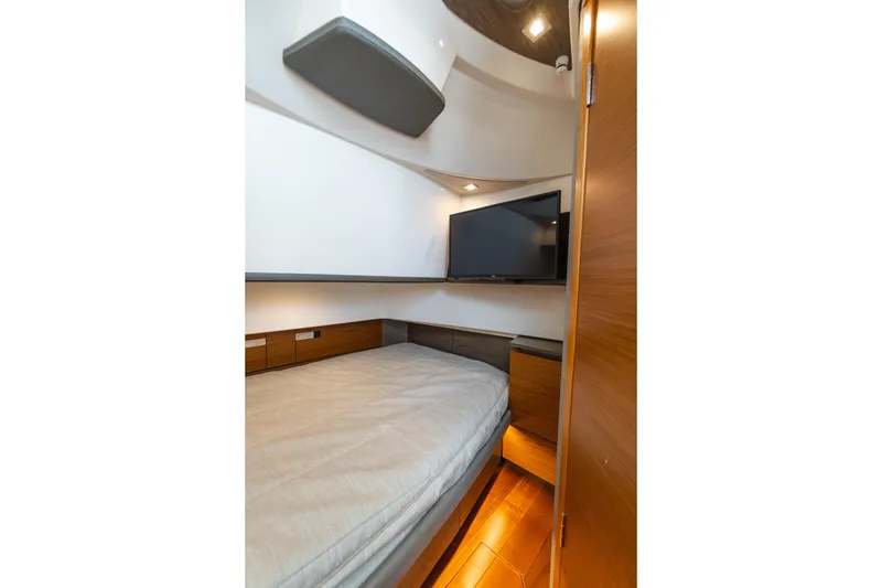Slide: The Image of 2020 Tiara Sport 38 LS cabin interior with bed, TV, and wooden accents. - 27
