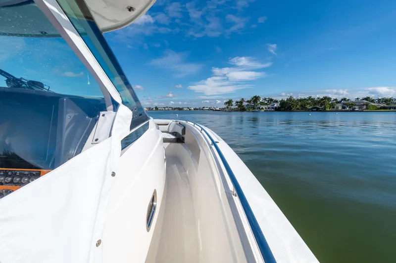 Slide: The Image of 2020 Tiara Sport 38 LS boat cruising on a calm, scenic waterway under a clear blue sky. - 29