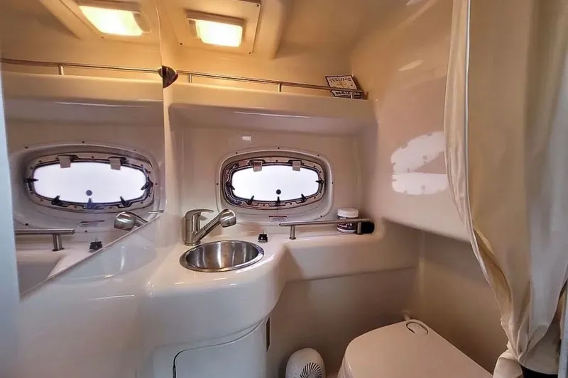 Slide: The Image of 2010 Sea Ray Sundancer 260 bathroom with sink, mirror, and porthole windows. - 13