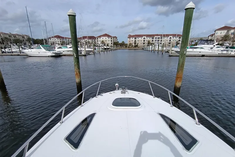 Slide: The Image of Bow view of 2010 Sea Ray Sundancer 260 in a marina with docked boats. - 26