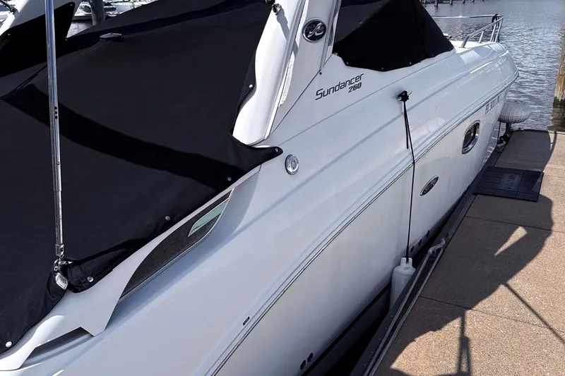 Slide: The Image of 2010 Sea Ray Sundancer 260 boat docked with black cover, side view. - 3