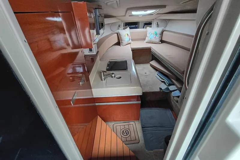Slide: The Image of Interior of 2010 Sea Ray Sundancer 260 with cozy seating and compact kitchenette. - 30