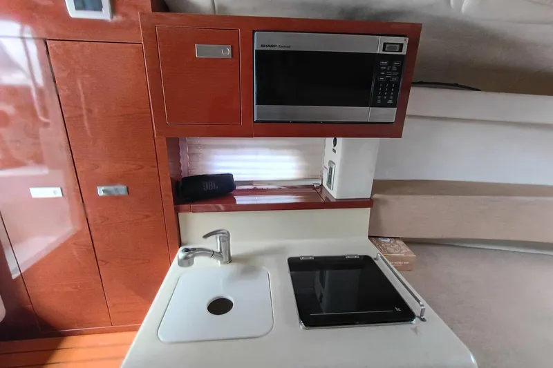 Slide: The Image of 2010 Sea Ray Sundancer 260 interior kitchen with microwave, sink, and stove. - 32