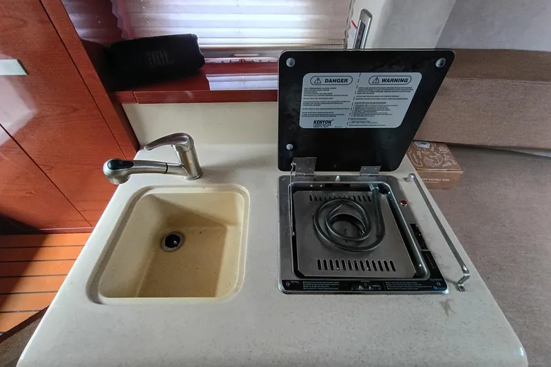 Slide: The Image of 2010 Sea Ray Sundancer 260 galley with sink and stove, featuring modern design. - 34