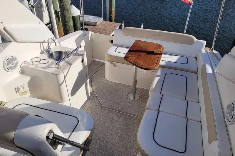Slide: The Image of 2010 Sea Ray Sundancer 260 boat interior with seating, table, and sink by the water. - 6