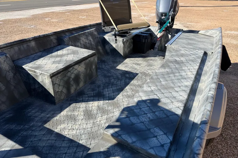 Slide: The Image of 2025 WeldBilt 1448 boat interior with textured flooring and motor, parked on gravel. - 4