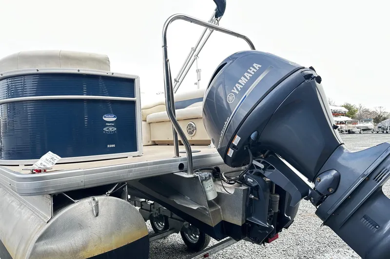 Slide: The Image of 2015 Godfrey 2286 Sweetwater Pontoon with Yamaha outboard motor, docked on gravel. - 2