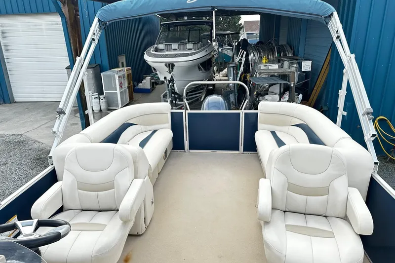 Slide: The Image of 2015 Godfrey 2286 Sweetwater Pontoon with white seating, parked in a storage area. - 5