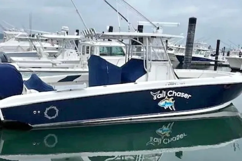 The Image of 2008 Fountain 34 Center Console boat docked, named "Tail Chaser," with blue and white design. - 0