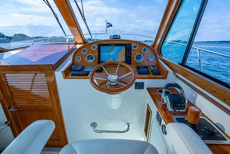 Slide: The Image of 2016 Hinckley Talaria 34 helm with wooden accents and navigation equipment, overlooking the ocean. - 11